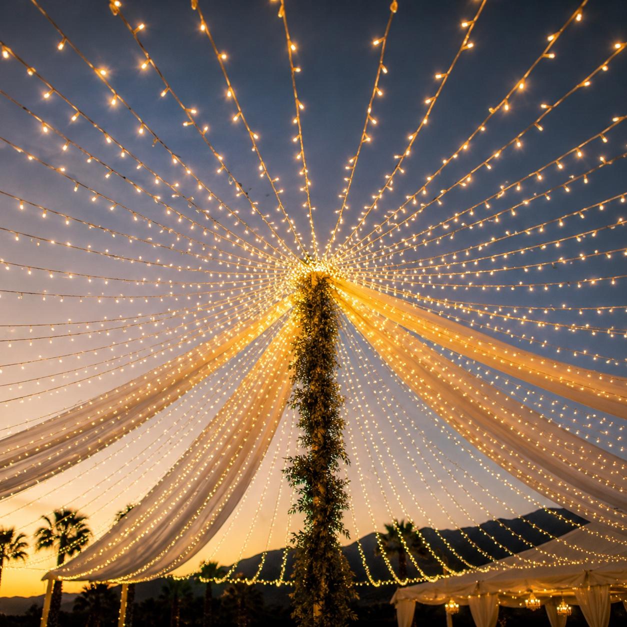 String-lights canopy at Mi Amor Ranch looking up at the palm-wrapped center pole at dusk